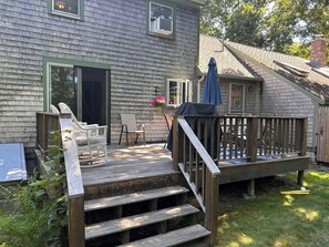 Eine Terrasse mit Holzwertkante, eine Treppe, die zu einem Haus mit einer grünen Tür führt, und ein Terrassenstuhl.