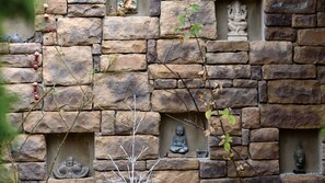 Eine Steinsäule mit mehreren Nischen, die Statuen und eine Buddha-Figur beherbergen.