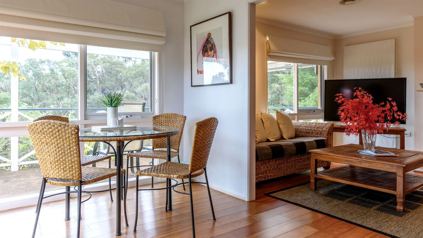 A living room with a glass table, wicker chairs, a sofa, and a TV.