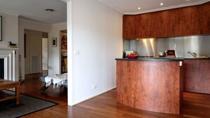 A modern kitchen with wooden cabinets, a central island, and a dining area with a fireplace. - Impressive Moroccan Style Vacation Rental with Spa Bath in Daylesford, Victoria (Daylesford)