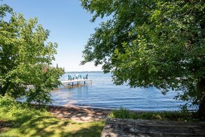 A lakeside view with a dock and chairs.
