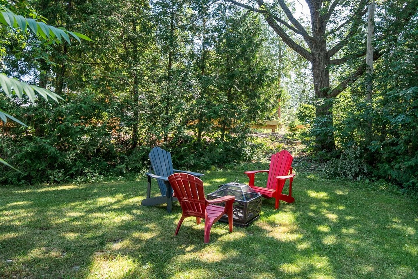 Un espace extérieur aménagé avec deux fauteuils Adirondack et une table à plateau en verre.
