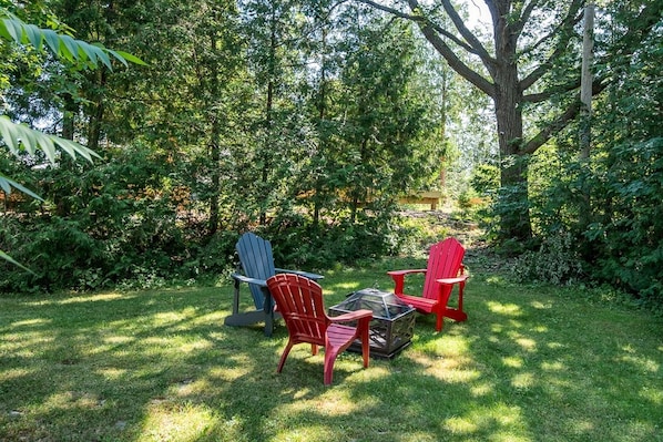 An outdoor seating area with two Adirondack chairs and a glass-top table.