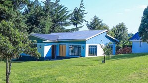 Una casa moderna de dos pisos con techo inclinado, ventanas grandes y césped cuidado.