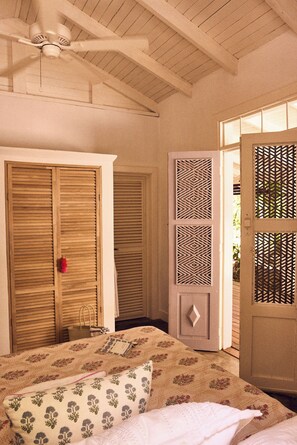 A bedroom with a bed, a wardrobe, a door with a decorative panel, and a ceiling fan. - Serene 4-bedroom house in Guanacaste, Costa Rica, perfect for relaxing getaway (Los Pargos)
