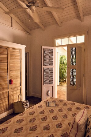 A bedroom with a bed, a wooden wardrobe, a door with a geometric pattern, and a view of greenery outside. - Serene 4-bedroom house in Guanacaste, Costa Rica, perfect for relaxing getaway (Los Pargos)