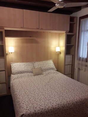 A bed with floral bedding, two wall-mounted lamps, and a ceiling fan. - Casa sant'Apollonia (Sant'Apollonia)