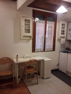 A small kitchen with a wooden chair, a white countertop, and a cabinet above the sink. - Casa sant'Apollonia (Sant'Apollonia)