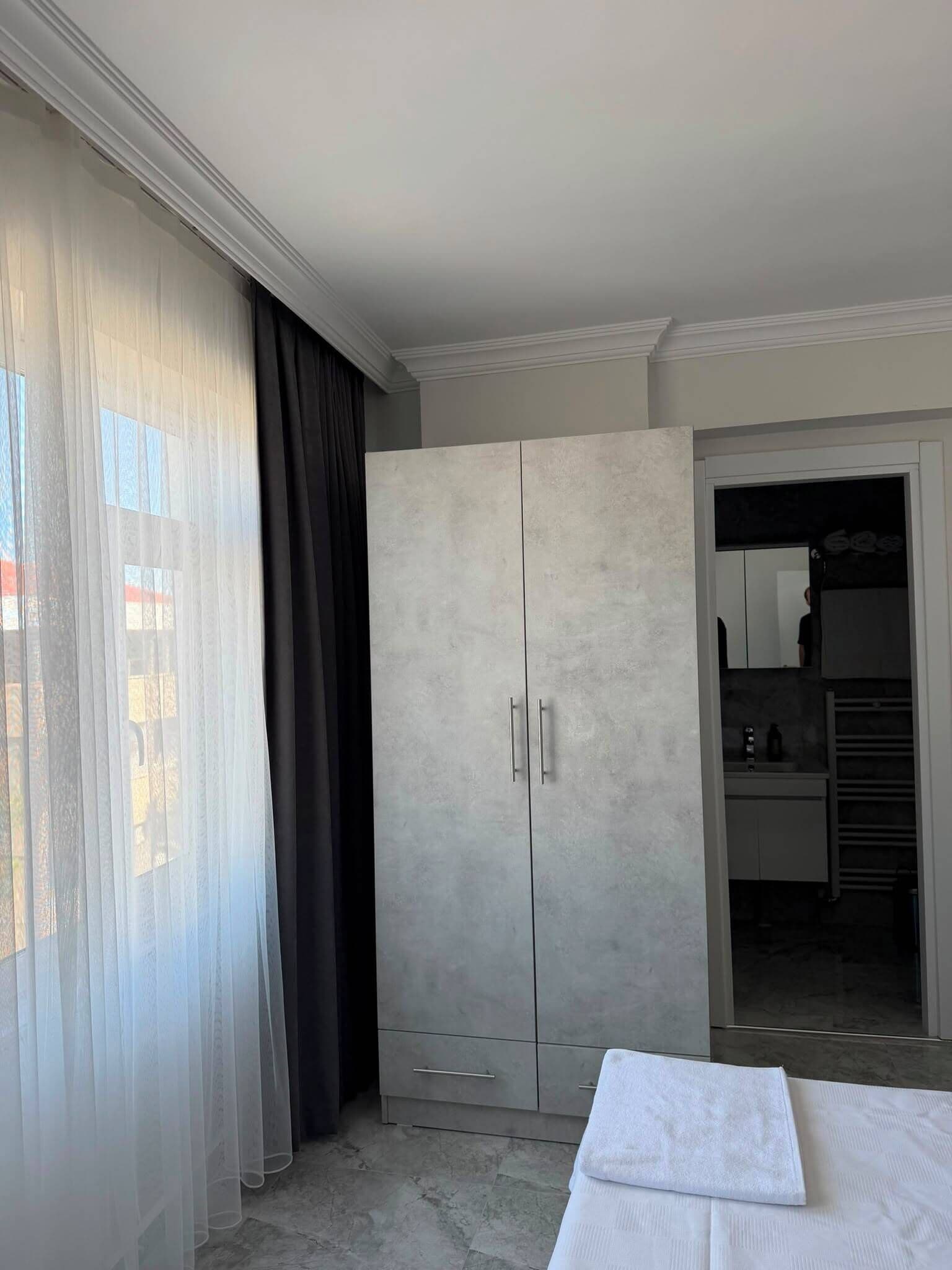 A bedroom with a large wardrobe, a bed, and a bathroom visible through an open door.