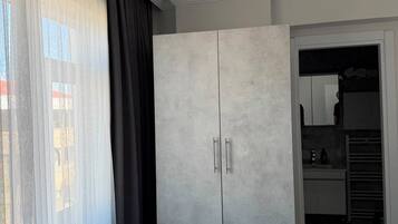 A bedroom with a large wardrobe, a bed, and a bathroom visible through an open door.