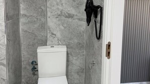 Ein Badezimmer mit Toilette, Dusche und einem an der Wand befestigten Fön.