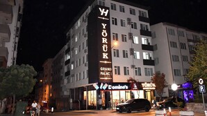 Ein mehrstöckiges Gebäude mit beleuchteter Beschilderung für 'YORUK GRAND PALACE' und einem Schild für Domino's Pizza.
