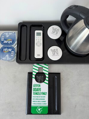 A set of hotel amenities including a remote control, a kettle, and a set of keys.