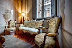 Ein Zimmer mit einem Vintage-Sofa, zwei Sesseln und einer Stehlampe.