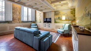 A spacious living room with a large sectional sofa, a television, and a mural on the wall. - PONTEVECCHIO, featuring original 17th-century furnishings and frescoes (Firenze)