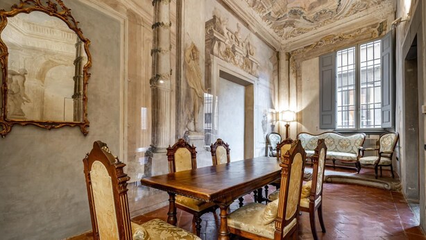 A formal dining room with a large wooden table, ornate chairs, and a mirror on the wall. - PONTEVECCHIO, featuring original 17th-century furnishings and frescoes (Firenze)
