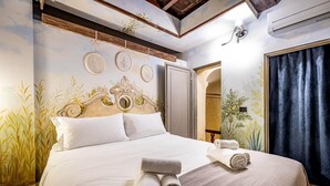 A neatly made bed with rolled towels, a headboard with decorative elements, and wall art. - PONTEVECCHIO, featuring original 17th-century furnishings and frescoes (Firenze)
