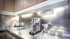A modern kitchen with stainless steel appliances, including a coffee maker and a kettle, and two mugs with coffee-related text. - PONTEVECCHIO, featuring original 17th-century furnishings and frescoes (Firenze)