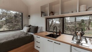 Une chambre à coucher de taille modeste, comprenant un lit, une table de chevet et une fenêtre donnant sur des arbres.