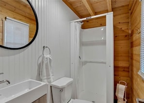 A bathroom with a shower, toilet, and sink.