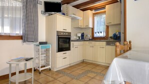 Una cocina compacta con horno integrado, cafetera y una pequeña mesa con una cesta.