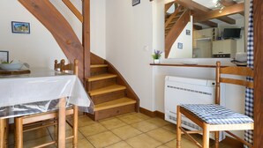 Una cocina con estufa integrada, una mesa de comedor con sillas y una escalera con vigas de madera.