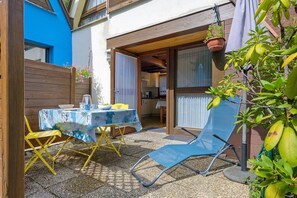 Un patio exterior con una mesa lista para comer, un sillón azul y una valla de madera.