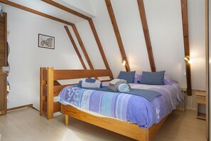 Un dormitorio con una cama de madera, una ventana con persianas, una lámpara de pared e imagen enmarcada.