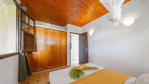 A room with a bed, a wooden wardrobe, a window with blinds, and a ceiling with wooden beams. - Villa Zenaida, a villa near the sea (Sainte-Luce)