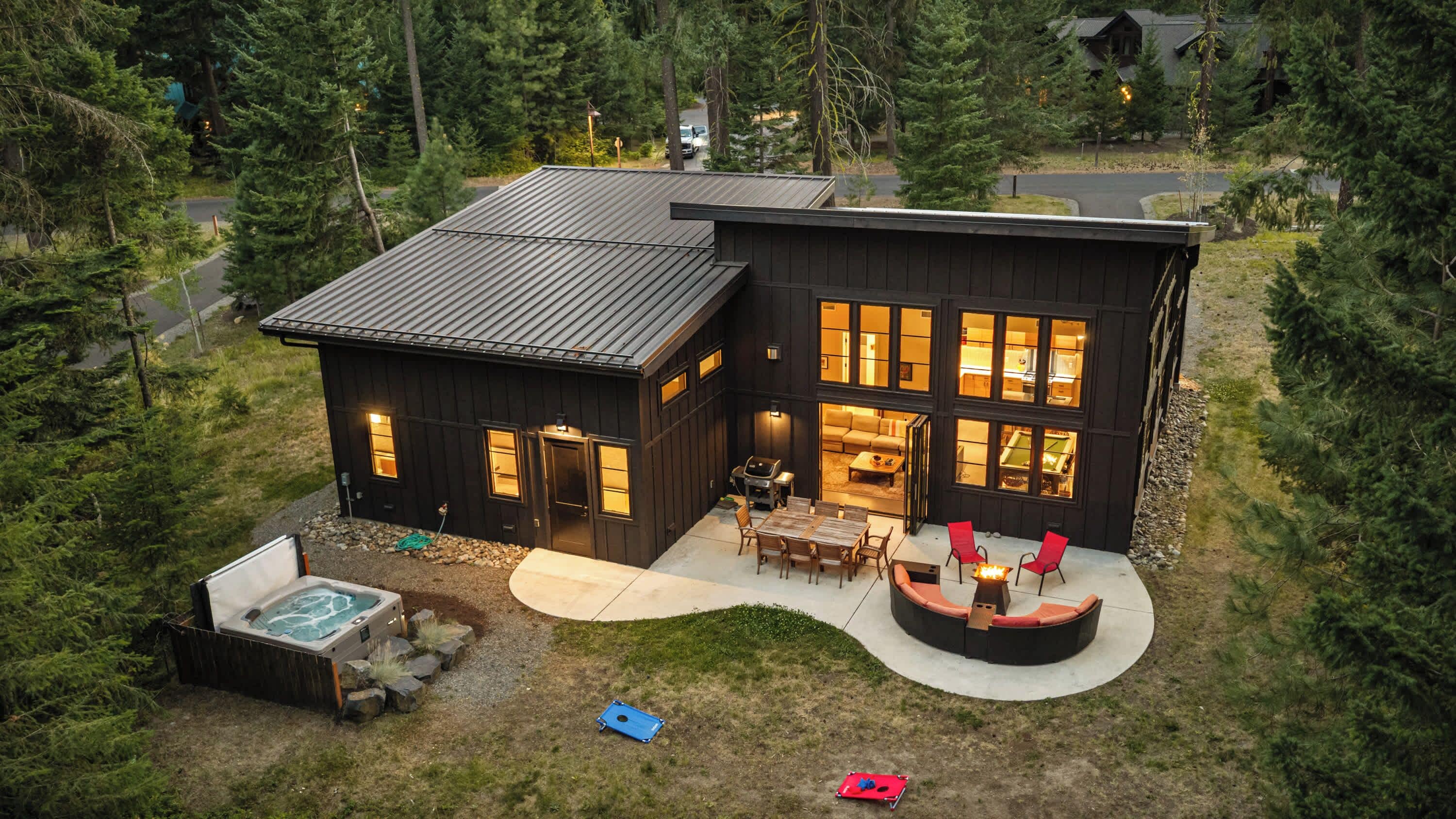A modern two-story house with a hot tub, outdoor seating, and a well-maintained yard.