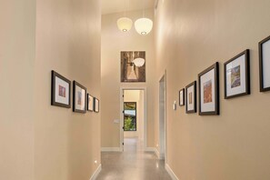 A hallway with framed pictures on the walls, a ceiling light, and a door at the end. - 4BR, Hot Tub, Firepit, Fireplace, Pet Friendly (Cle Elum)