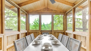 Comedor con una larga mesa dispuesta para una comida, rodeado de paredes de paneles de madera y grandes ventanales.