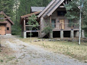 A log cabin with a stone foundation, a wooden deck, and a staircase leading to the entrance. - Family friendly 4 bedroom cabin, located in Star Valley Ranch. (Star Valley Ranch)