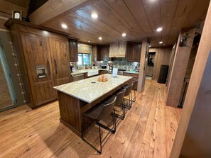 A modern kitchen with wooden cabinets, a granite countertop, and bar stools. - Family friendly 4 bedroom cabin, located in Star Valley Ranch. (Star Valley Ranch)