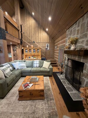 A cozy living room with a sectional sofa, a wooden coffee table, a fireplace, and a staircase. - Family friendly 4 bedroom cabin, located in Star Valley Ranch. (Star Valley Ranch)