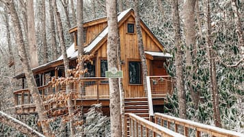 A wooden cabin with a balcony, surrounded by trees.