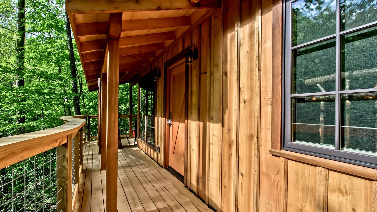 A wooden cabin with a covered porch and large windows.