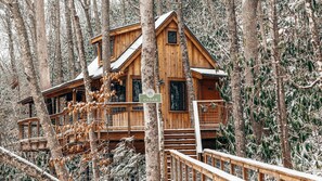 A wooden cabin with a balcony, surrounded by trees. - Incredible, Cozy Tree House in Gatlinburg, Tennessee (Gatlinburg)