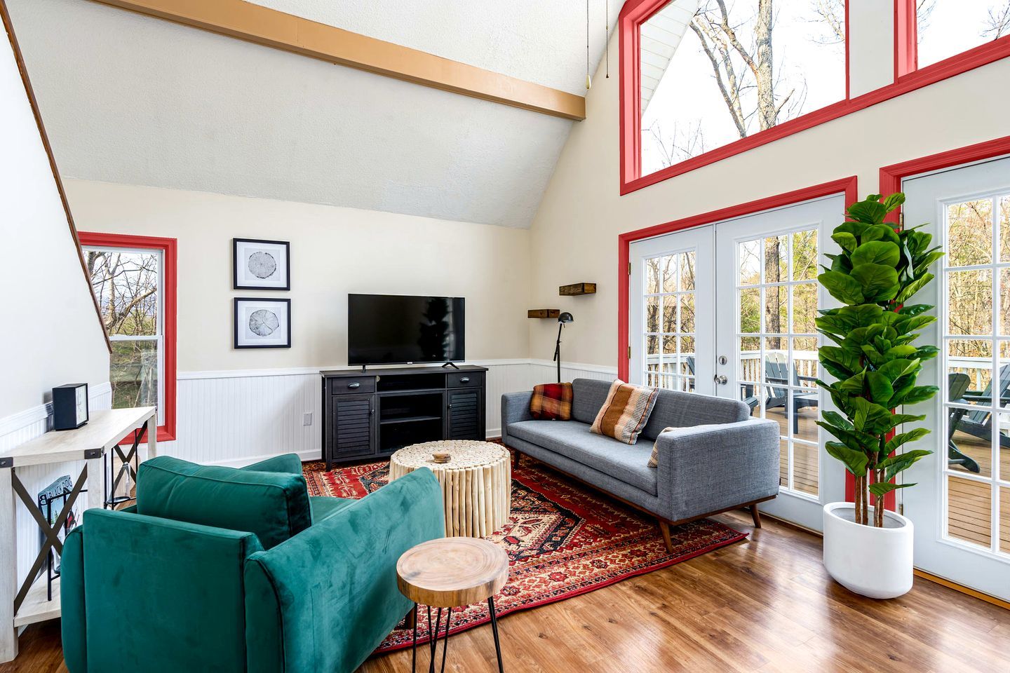 A living room with a sofa, green armchairs, a round coffee table, a TV, and a large potted plant.