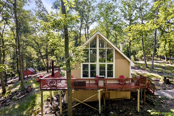 A cabin with a deck, surrounded by trees.