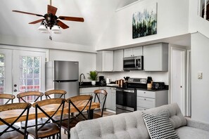 A modern kitchen with a dining area, featuring a ceiling fan, stainless steel appliances, and a dining table with chairs. - Updated Chalet-Cabin with Hot Tub, Fire Pit, Resort Amenities Surrounded by Amazing Views - the Perfect Getaway for Your Group in Hedgesville, WV (Hedgesville)