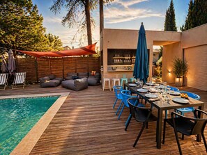 Ein Poolbereich mit Esstisch für vier Personen, umgeben von blauen Stühlen und einer Holzterrasse.