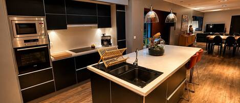 Una cocina moderna con una isla central, electrodomésticos integrados y un tragaluz.