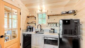 A compact kitchen with a dishwasher, coffee maker, and a refrigerator.