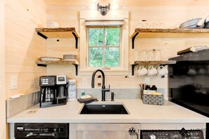 A modern kitchen with a central island, a built-in dishwasher, and a window with a view of greenery. - Secluded Tree House with Barbecue and Hot-tub in Gatlinburg, Tennessee (Gatlinburg)