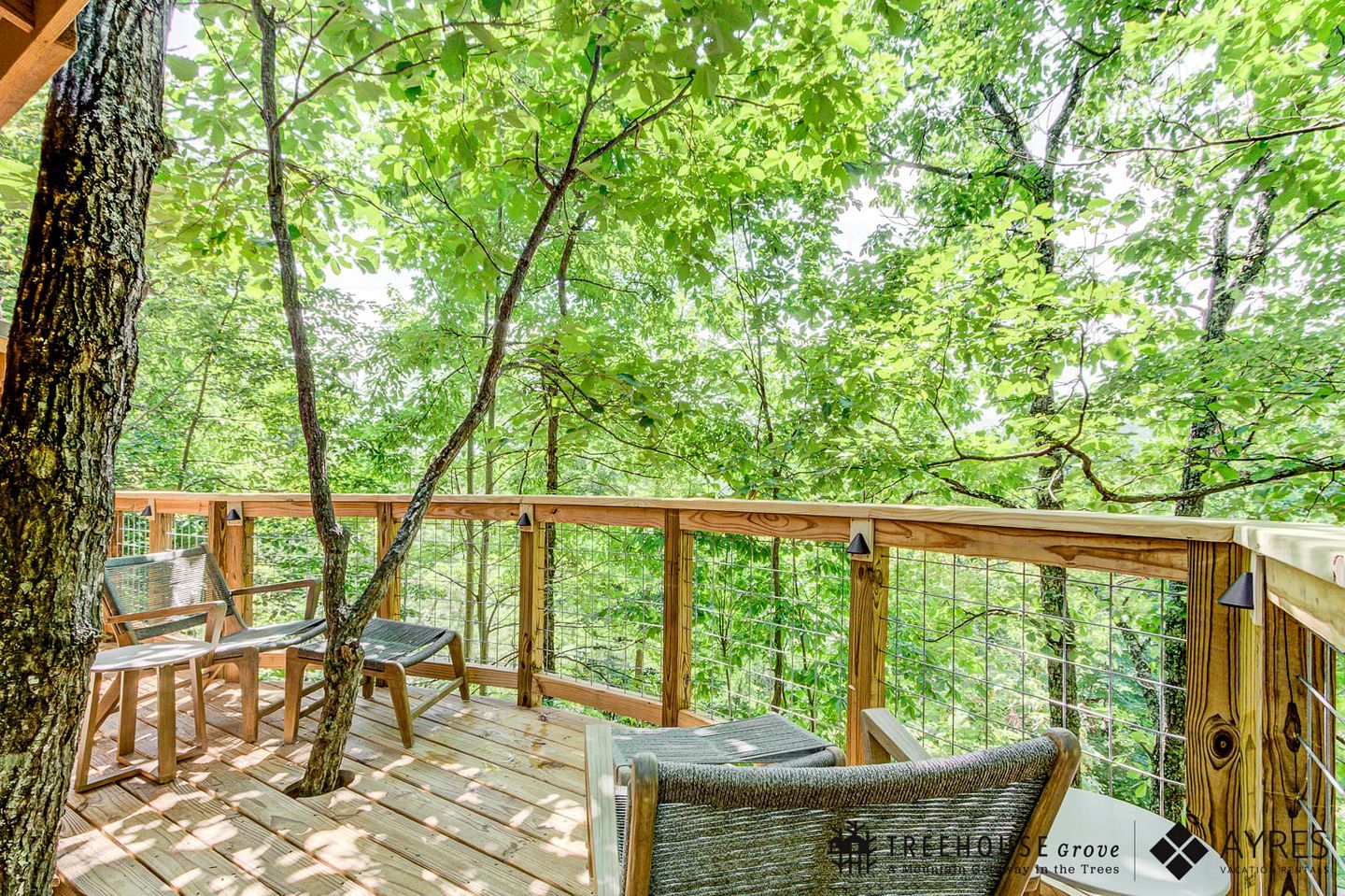 A wooden deck with seating, surrounded by trees.