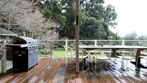 Eine Terrasse im Freien mit Grill, Metallstühlen und Tisch.