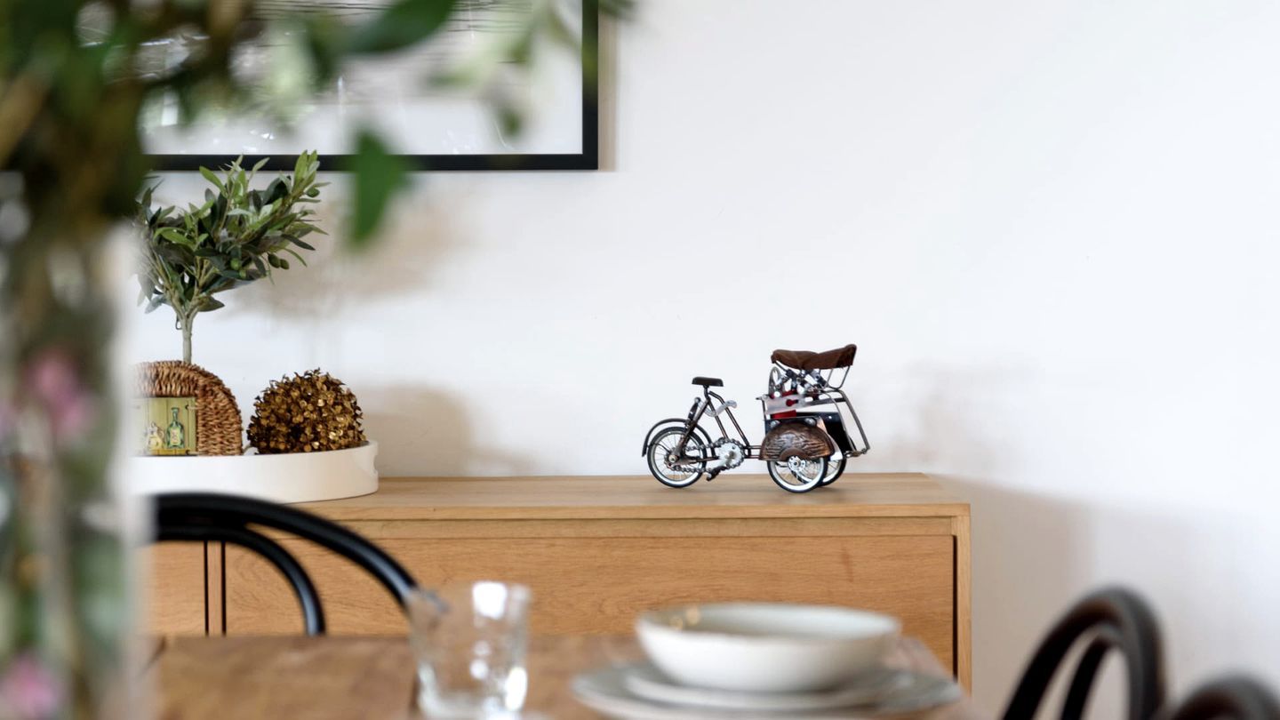 A dining table with plates, a glass, and a wooden cabinet with decorative items.