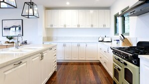 A modern kitchen with white cabinetry, a central island, a stove, and a sink.