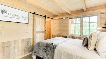 Une chambre confortable avec un lit, des murs en bois et une fenêtre.